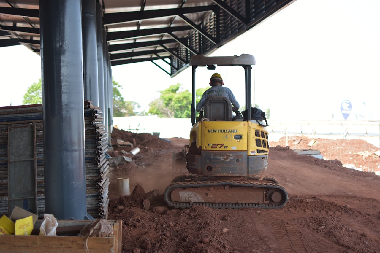 A construction worker maneuvering a bulldozer at an outdoor site, surrounded by dirt and equipment.